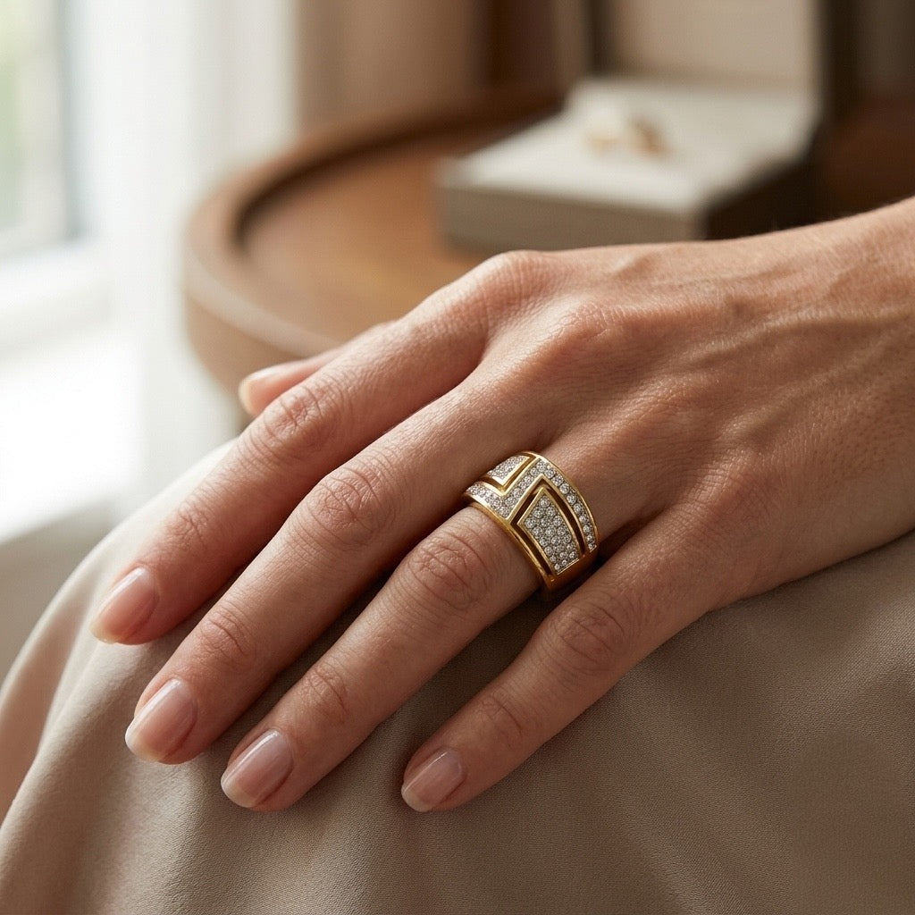 Hand wearing a gold ring with diamonds on a neutral background