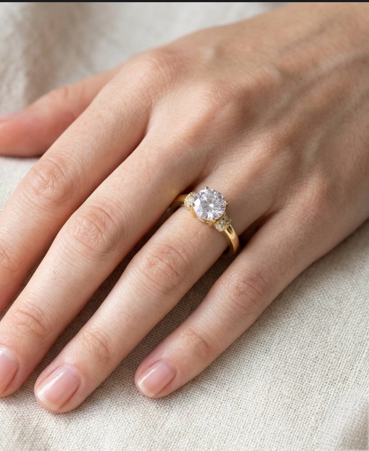 Gold ring with a diamond on a hand against a neutral background