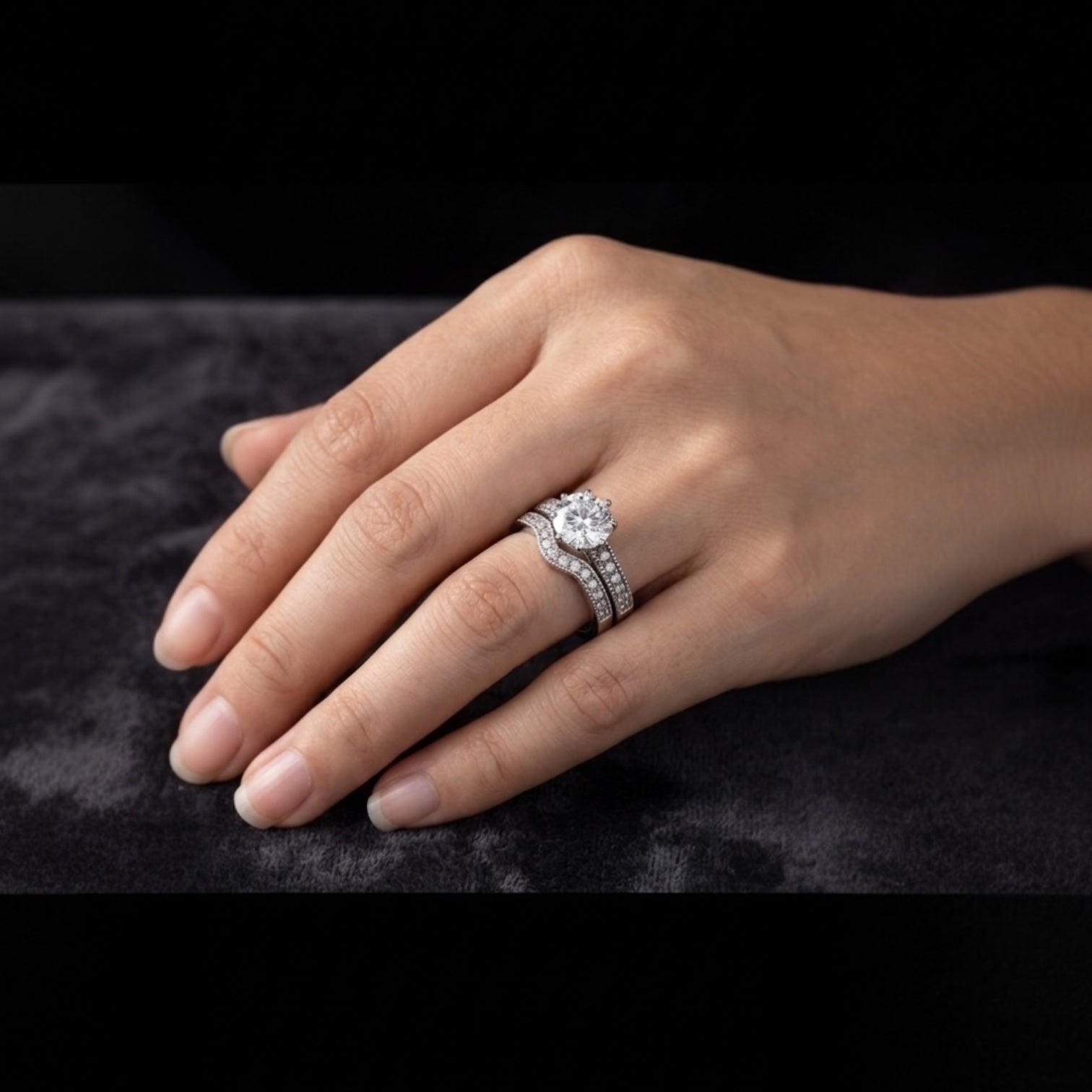 Hand wearing a diamond ring on a dark background